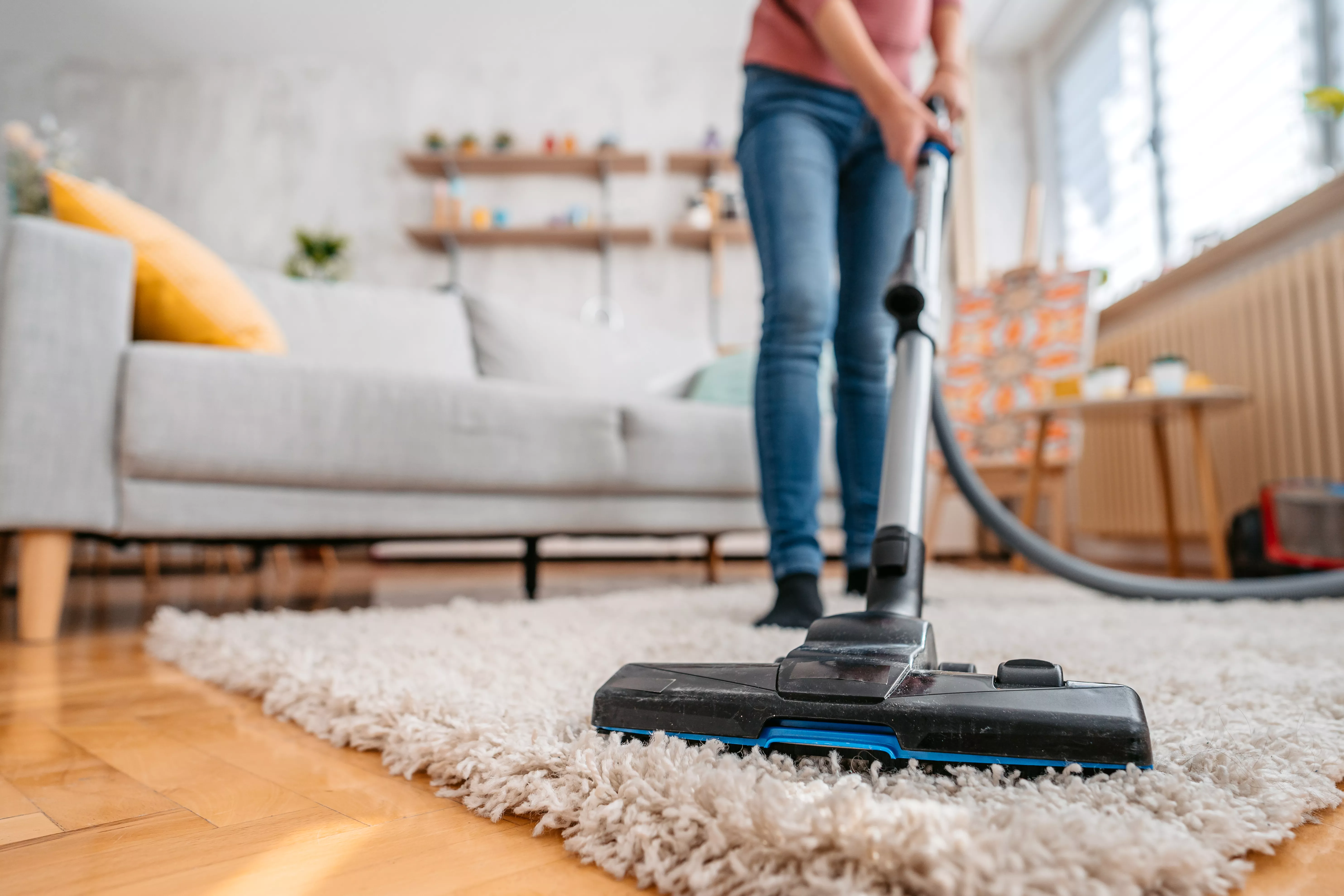 A woman vacuuming a living room rug.