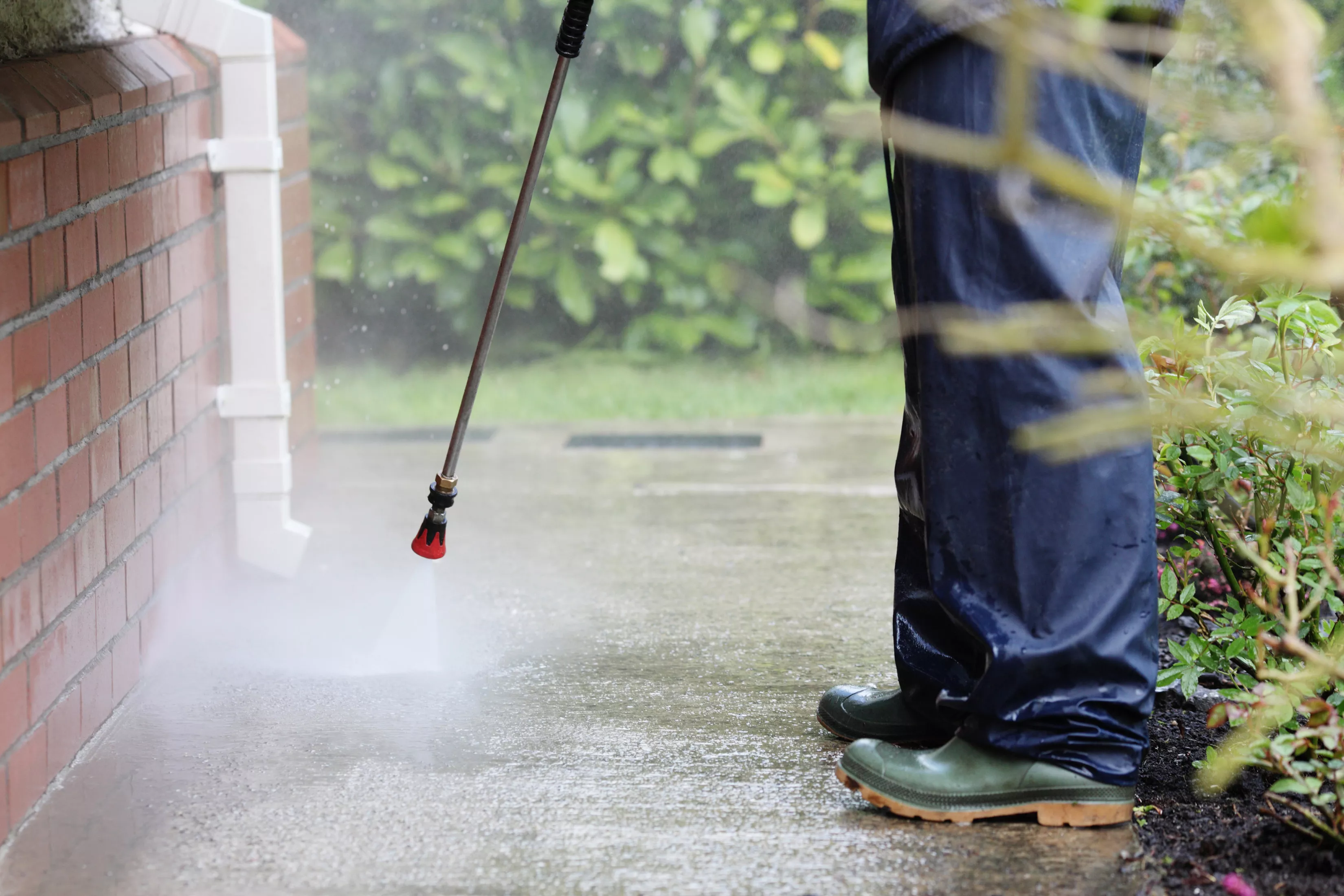 person pressure washing brick house and sidewalk