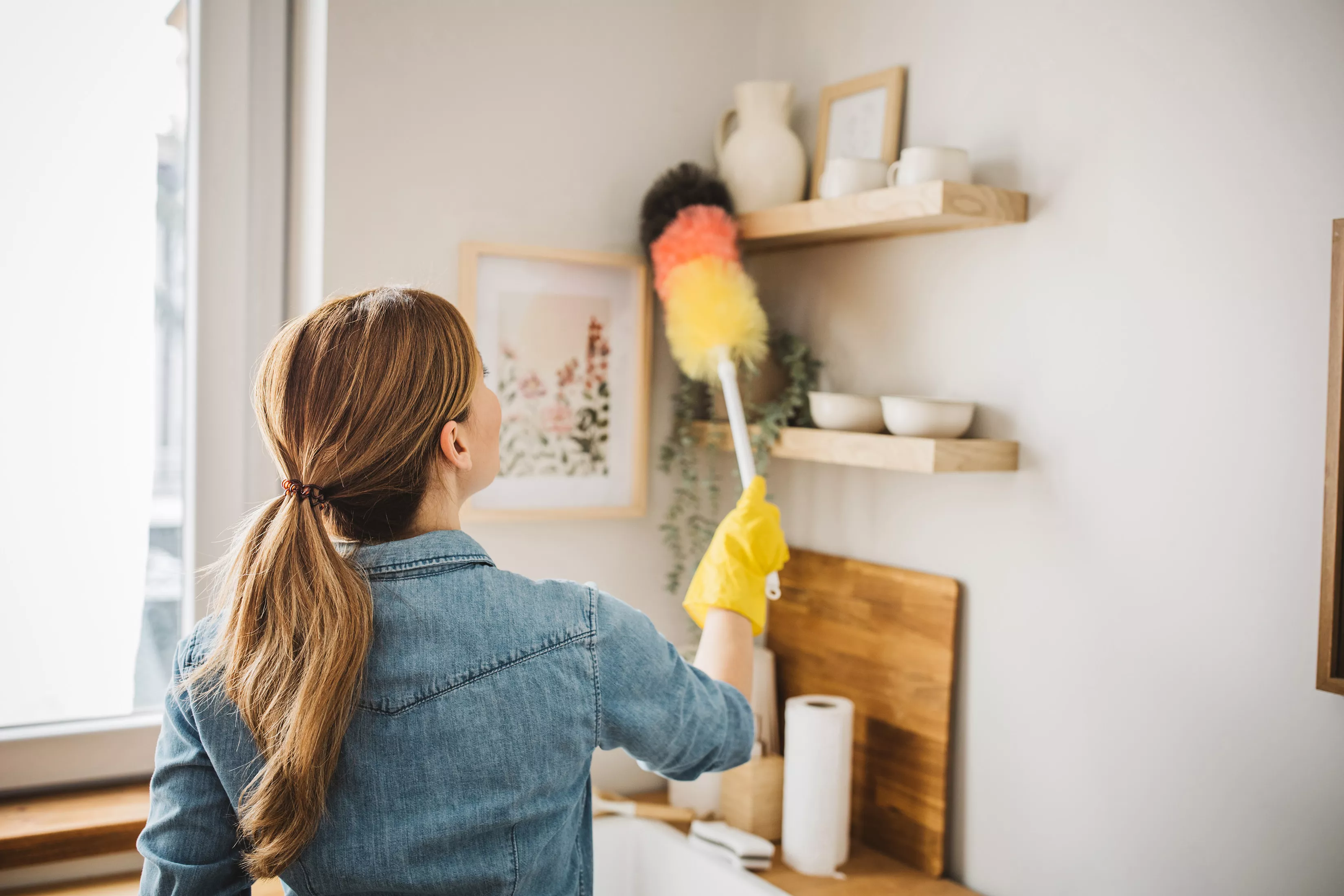 person dusting shelves in kitchen