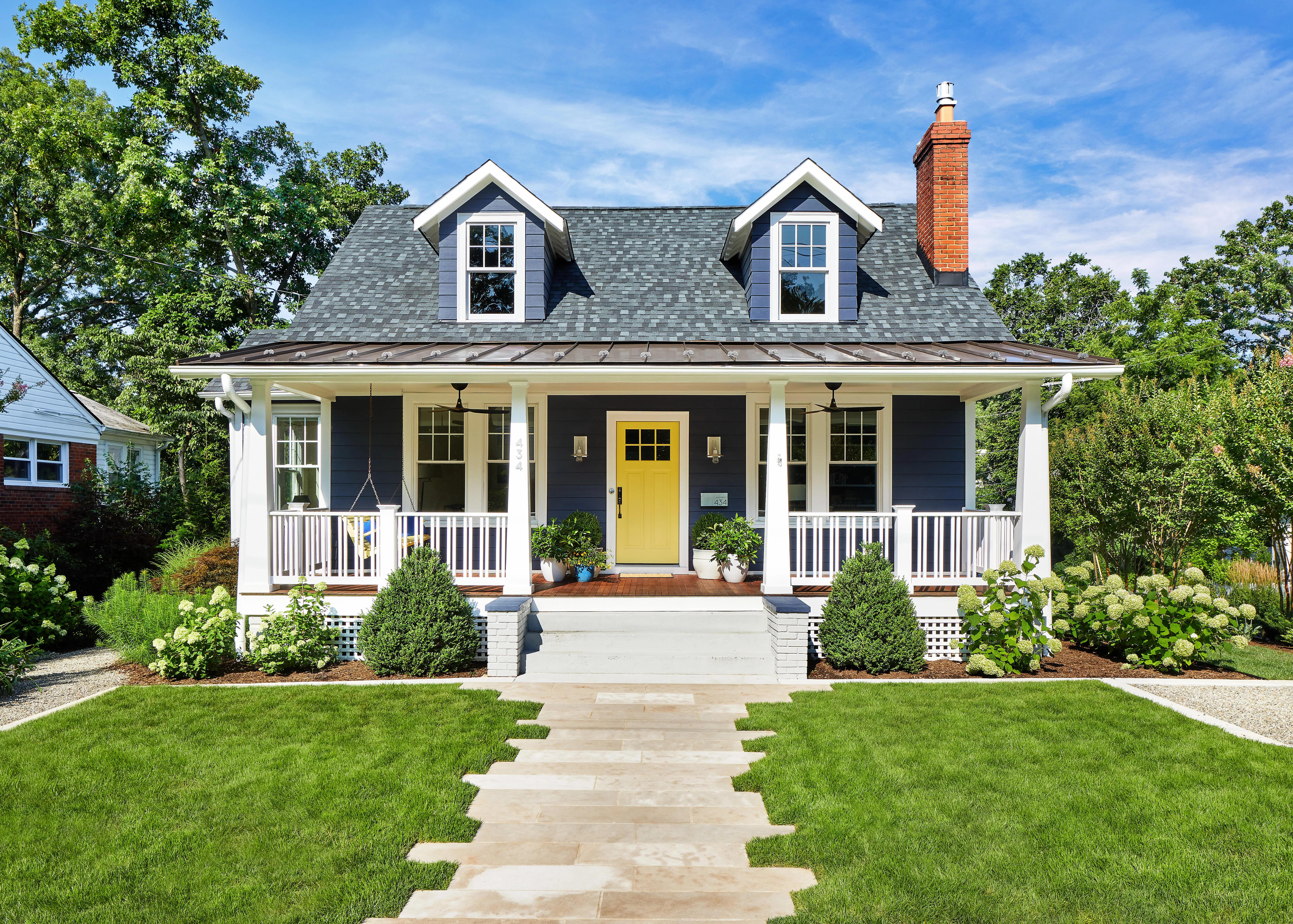 a small cute house with a yellow door and large front porch