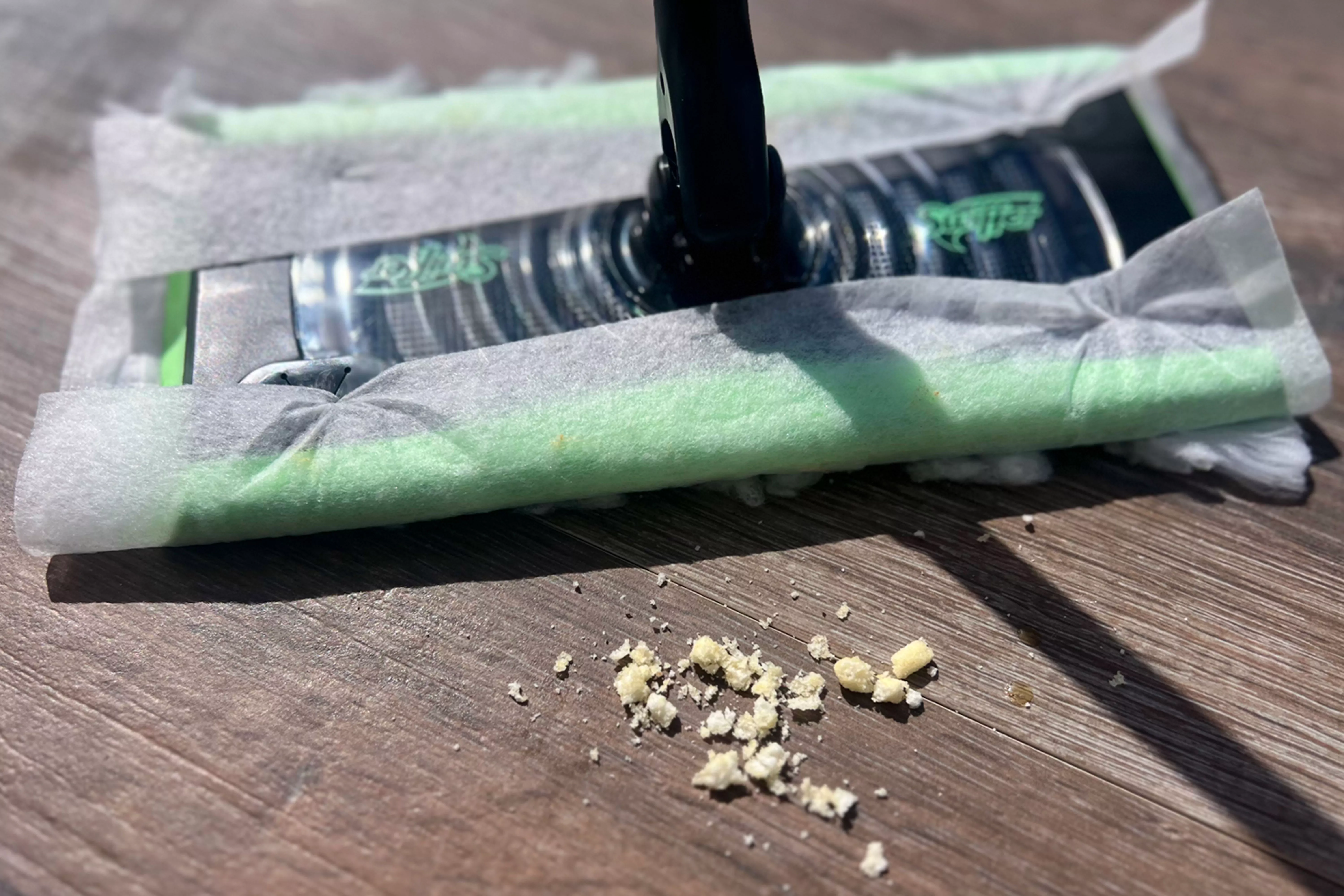 A Swiffer cleaning crumbs on a wooden floor